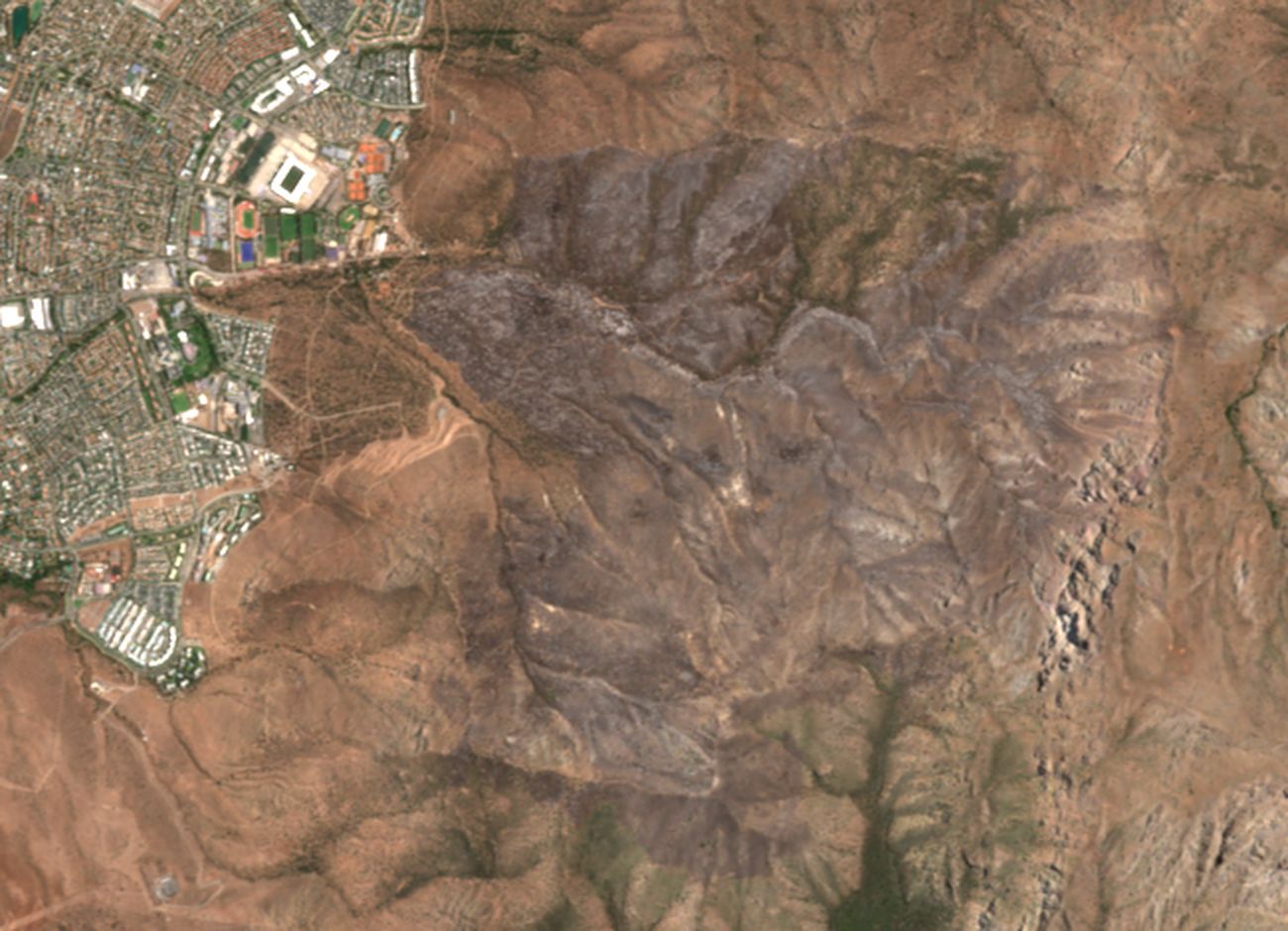 Imagen Sentinel-2 del 17 de enero de 2026: una mancha gris oscura cubre los cerros al oriente de San Carlos de Apoquindo tras el incendio de diciembre.